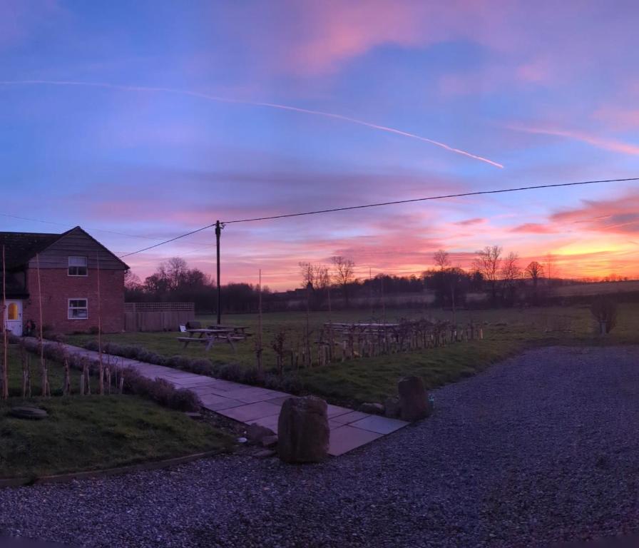 a sunset in a field with a house and a fence at Elderbrook House in Avebury