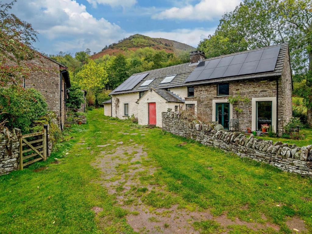 an old stone house with a red door in a yard at 3 Bed in Capel-y-Ffin 93362 