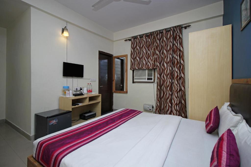 a bedroom with a large white bed with a television at Flagship 9046 Hotel Metro Star in New Delhi