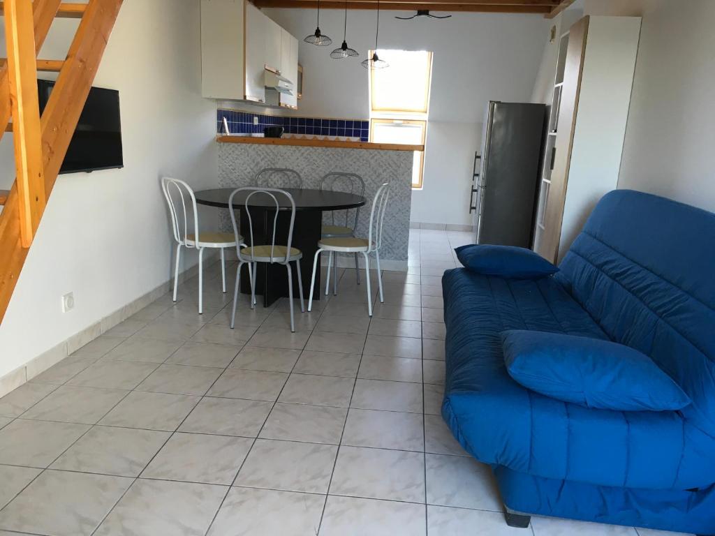 sala de estar con sofá azul y mesa en Roses des sables, en Jullouville-les-Pins