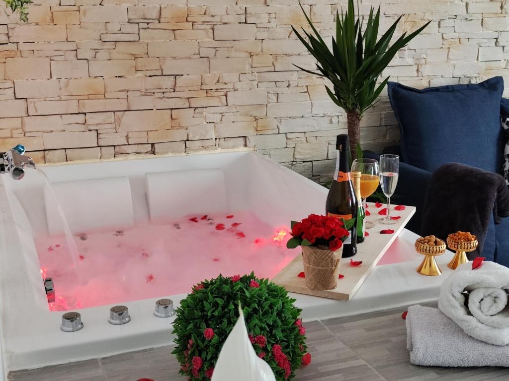 a bath tub filled with pink water with wine glasses at Romantic Cocon Home in Mulhouse in Mulhouse