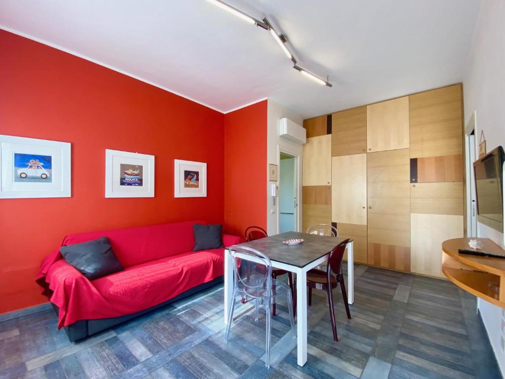 サン·ヴィンチェンツォにあるAppartamento Giuliaのリビングルーム(赤いソファ、テーブル付)