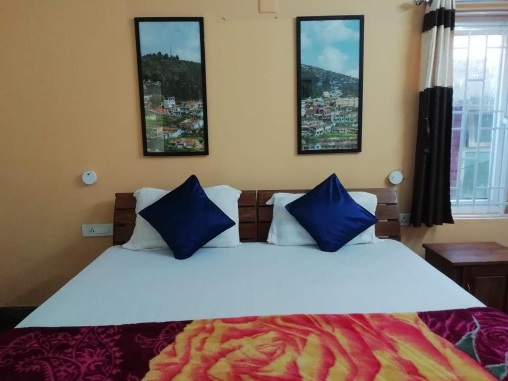 sypialnia z dużym białym łóżkiem z niebieskimi poduszkami w obiekcie Crystal homestay w mieście Utakamand