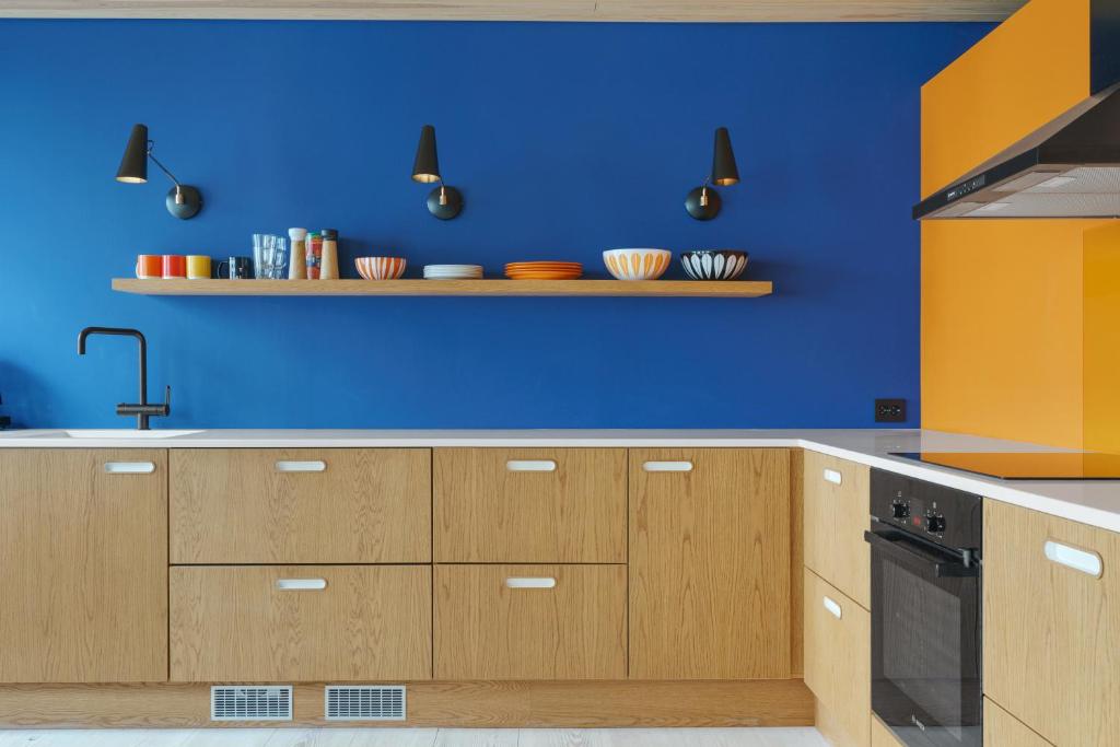 a blue kitchen with wooden cabinets and a blue wall at Unique gem overlooking the world famous Bryggen in Bergen