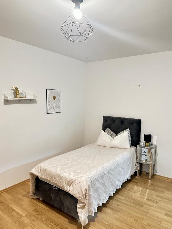 a white bedroom with a bed with a black headboard at FMI Apartmets next to Frankfurt Airport in Frankfurt/Main