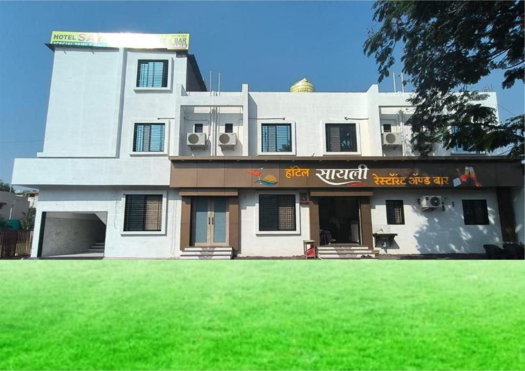 HOTEL SAYALI في Bhusāwal: مبنى أمامه حديقة خضراء
