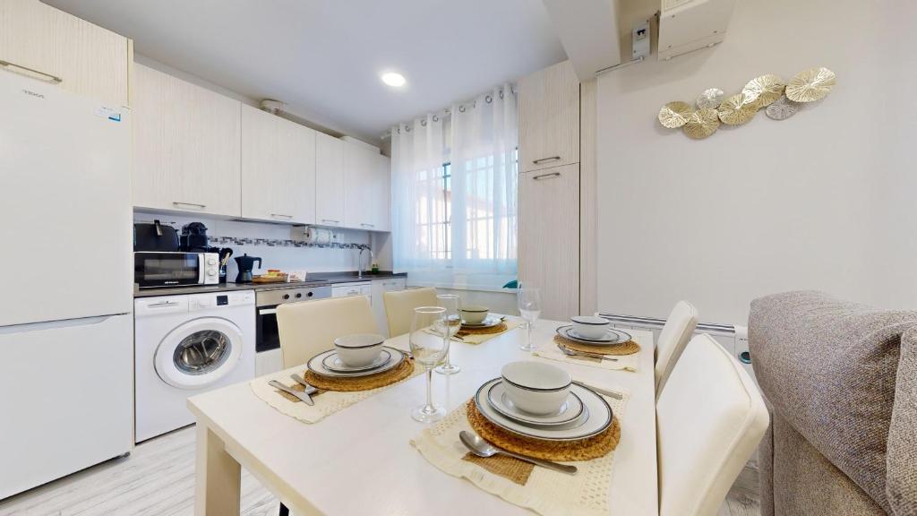 a white kitchen with a table with plates and dishes on it at Kastrexana Vivienda Turística con tranquilidad y wifi in Bilbao