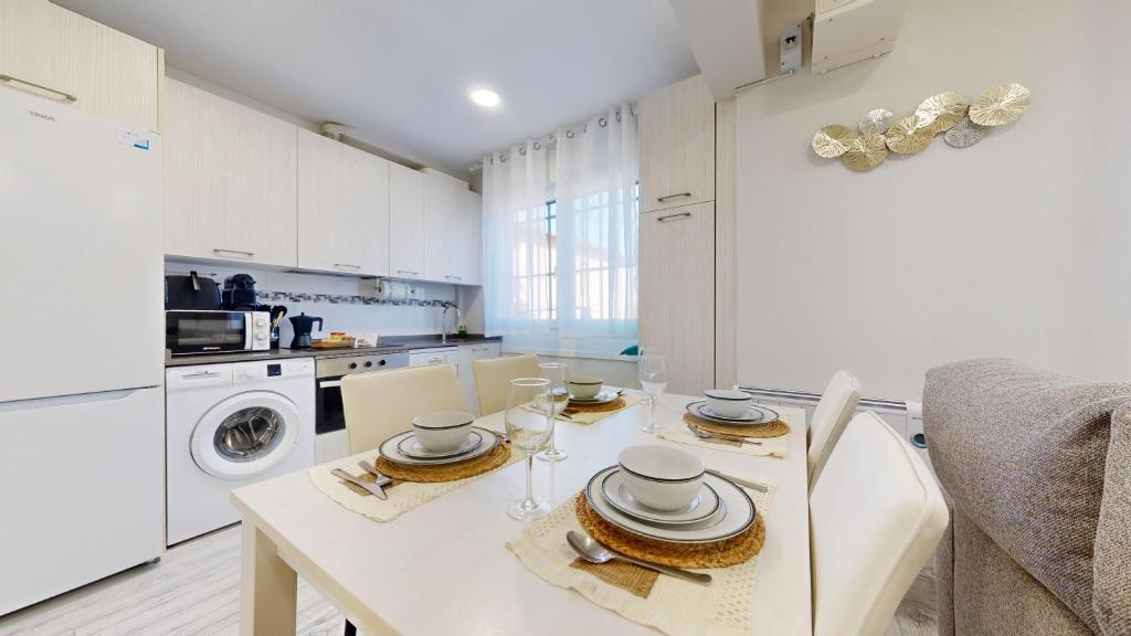 a white kitchen with a table with plates and dishes on it at Kastrexana Apartamento con tranquilidad y wifi in Bilbao