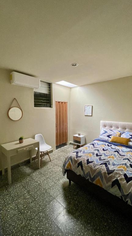 a bedroom with a bed and a table and a desk at Lindo espacio, cómodo y céntrico in San Salvador
