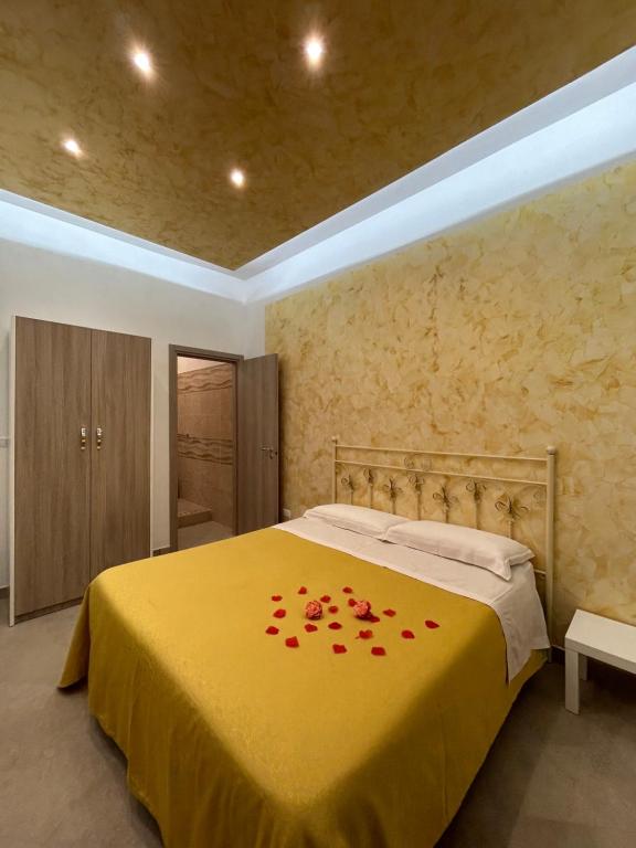 Un dormitorio con una cama amarilla con flores rojas. en A un passo dagli Dei, en Pimonte