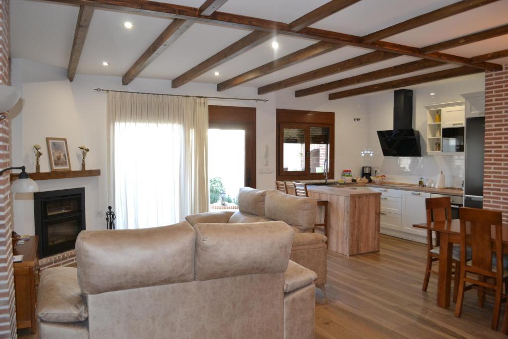 a living room with a couch and a kitchen with a table at Casa Rural La Madroña in Fuentelabrada de los Montes