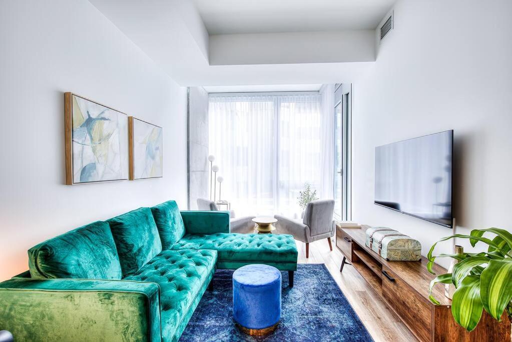 a living room with a green couch and a tv at Executive Suite Corporate stays Heart of Downtown in Montreal