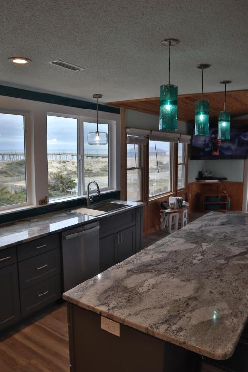 a kitchen with a granite counter top and some windows at Amazing Ocean View-Newly Renovated Modern Oasis in Avon