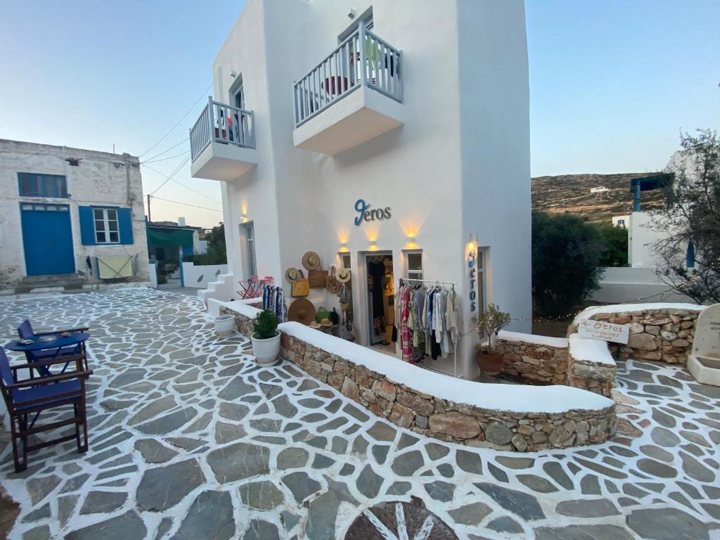 a white building with a stone courtyard with a store at Theros Apartments Donoussa in Donoussa