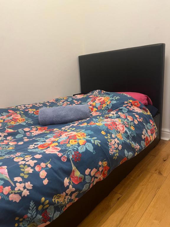 Ilford Tiny Jewel في إلفورد: سرير مع لحاف أزرق عليه زهور