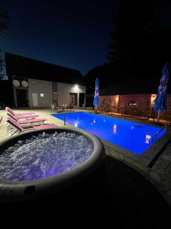 a swimming pool at night with chairs and umbrellas at Villa Mali Vuk in Banja Luka
