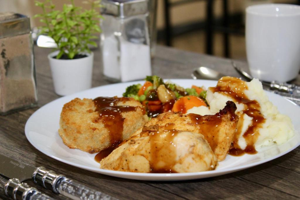 a plate of food with meat and vegetables on a table at Johal Mini Hotel -Birmingham City-FREE BREAKFAST in Birmingham