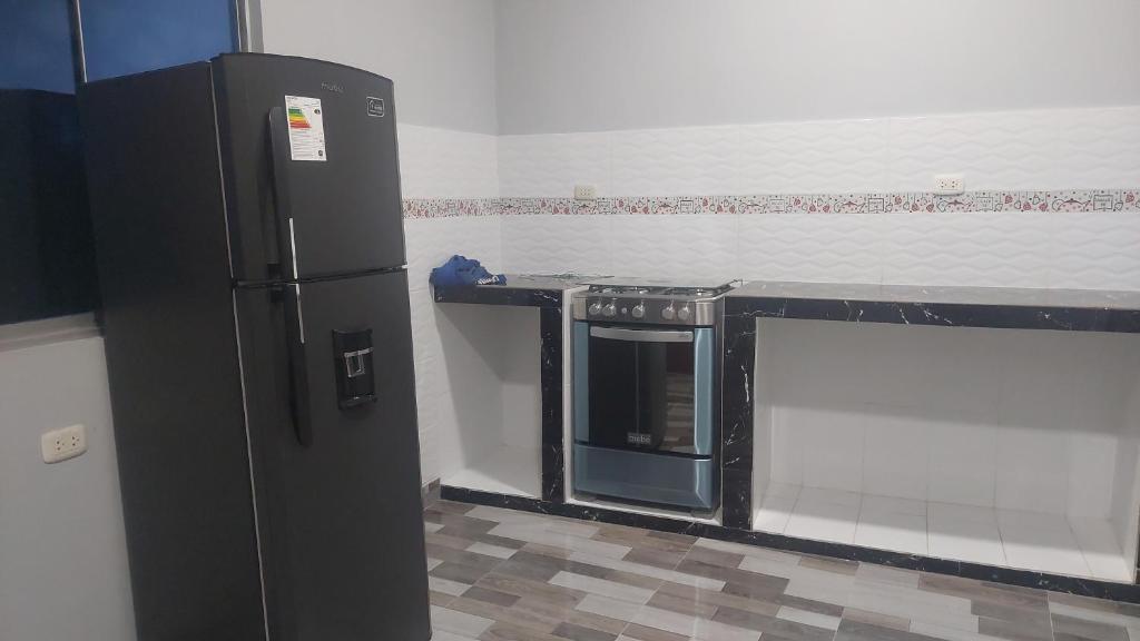 - une cuisine avec un réfrigérateur noir dans la chambre dans l'établissement Casa Alojamiento Picuro Lodgind, à Iquitos