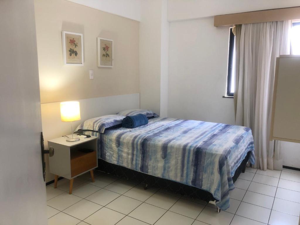 a bedroom with a bed and a table and a window at Flat Biarritz Próximo a Praia - Fonseca Imóveis in São Luís