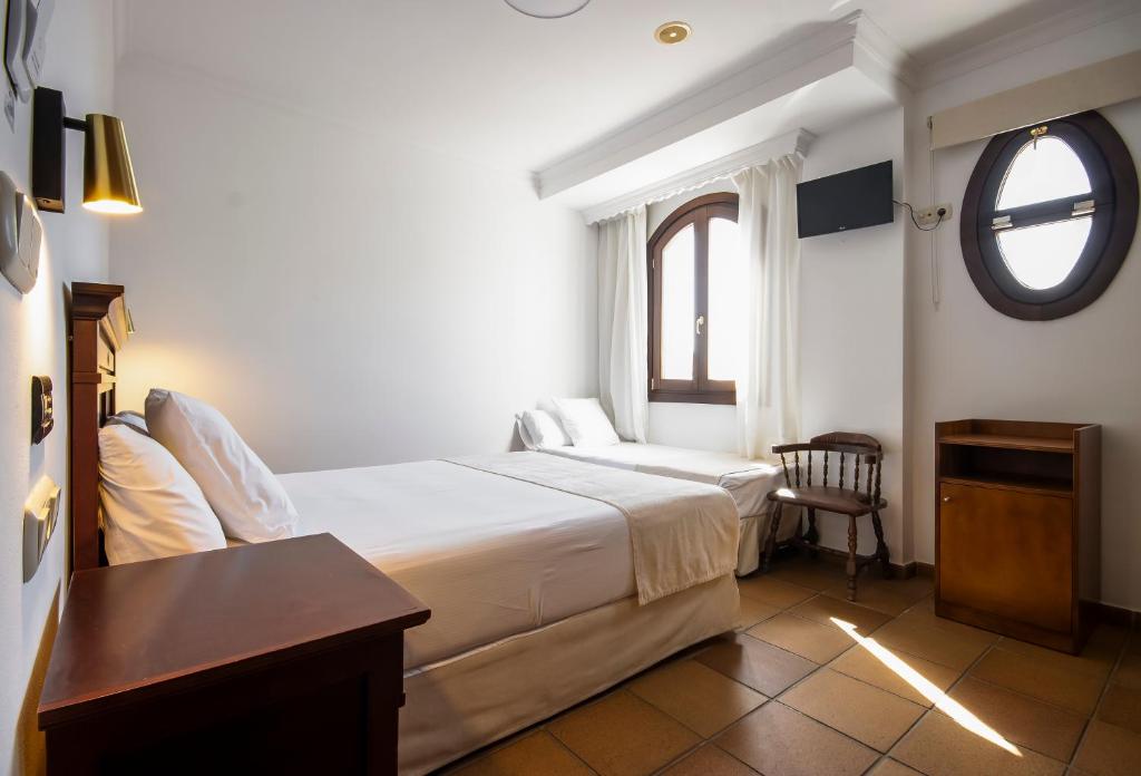 a hotel room with a bed and a window at Hostal La Muralla in Zahara de los Atunes