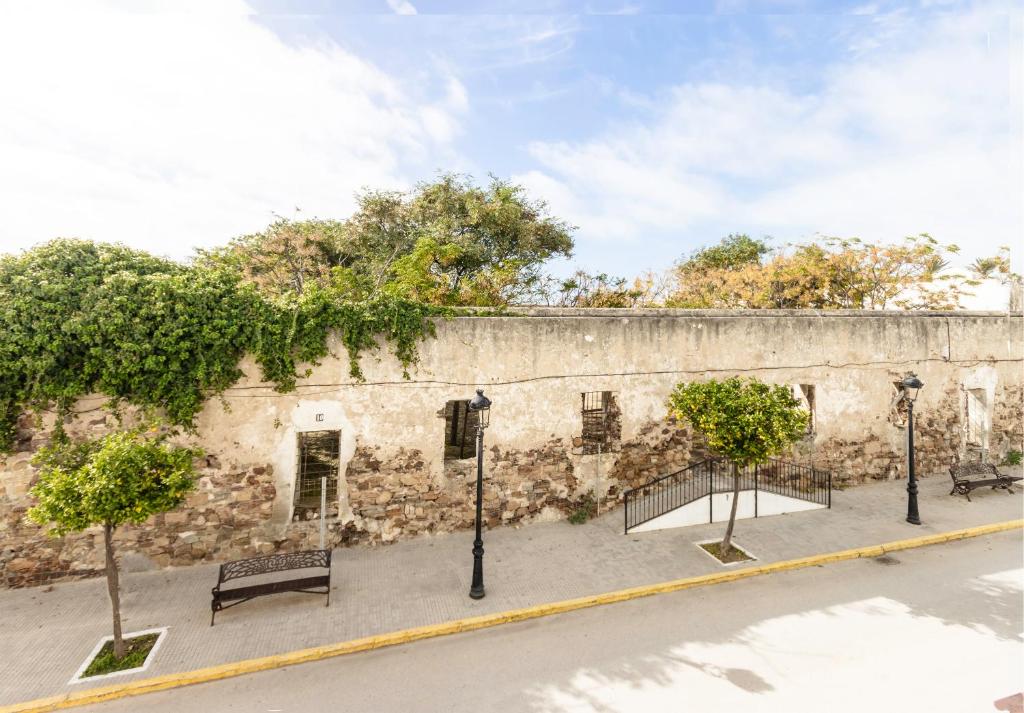 a stone wall with benches and trees in front of it at Hostal La Muralla in Zahara de los Atunes