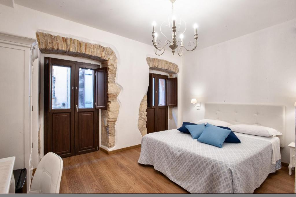 a white bedroom with a bed and a chandelier at Baco B&B in Cagliari