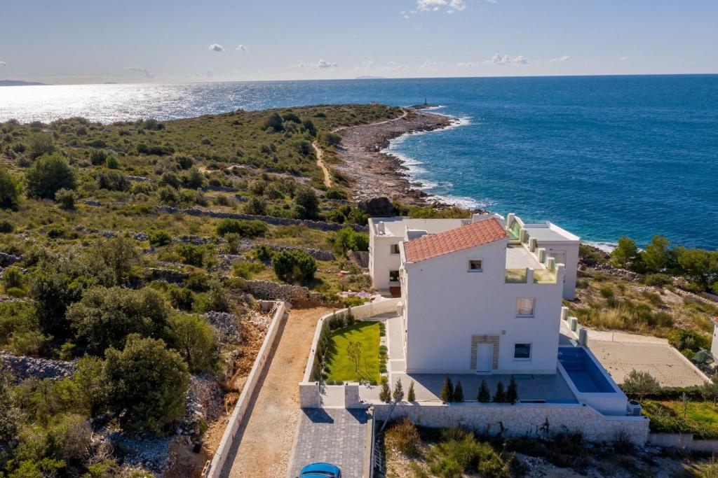 an aerial view of a white house next to the ocean at Villa Esquel - Beachfront, heated pool in Ražanj