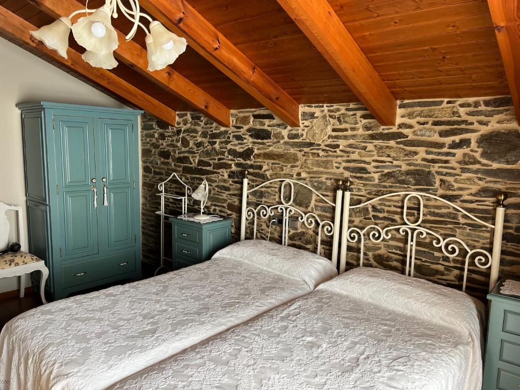 a bedroom with two beds and two blue cabinets at Casa Rural Dona María in Ordes