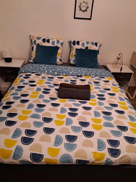 a bed with a blue and yellow comforter on it at Joli petit 2 pièces in Asnières-sur-Seine
