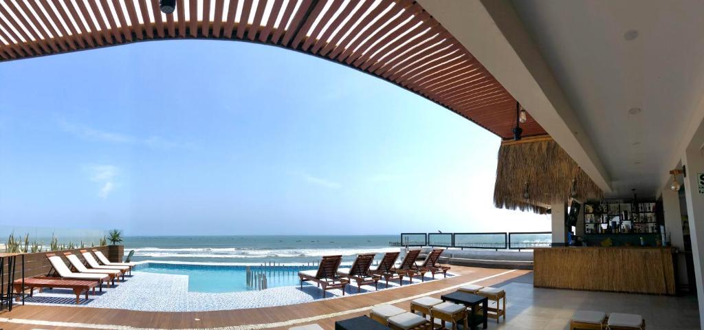 un resort con piscina, sedie e oceano di Hotel Pakatnamu a Pacasmayo