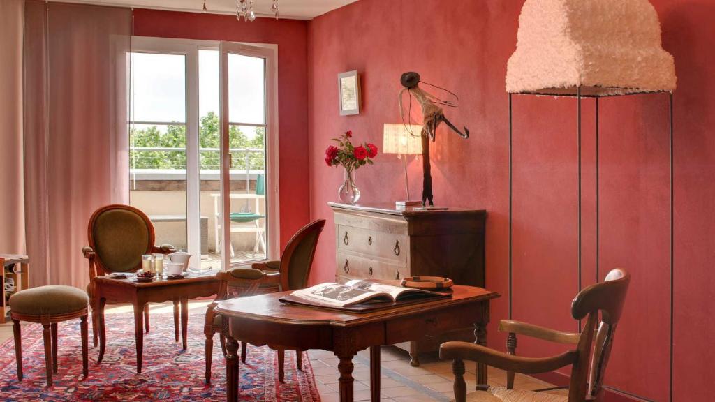 Cette chambre comprend une table, des chaises et un mur rouge. dans l'établissement Le Sénéchal, à Sauveterre-de-Rouergue