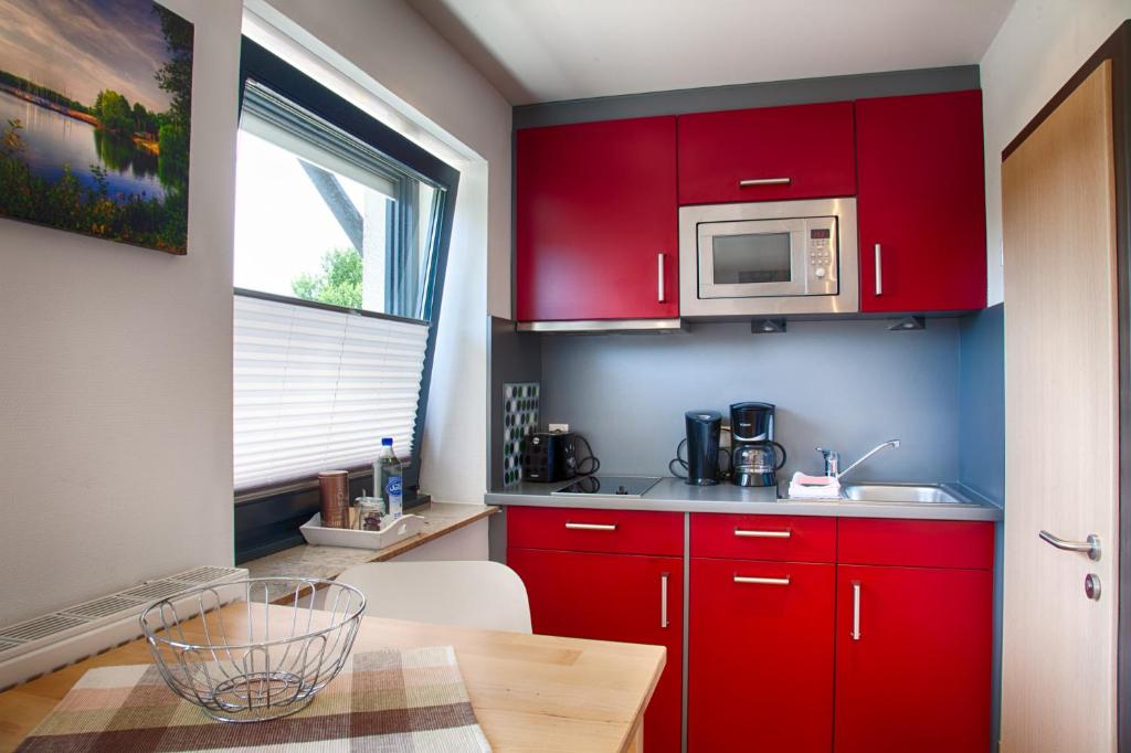 cocina roja con mesa y microondas en City-Apparte ONE - Auto-E-Ladestation, en Gronau