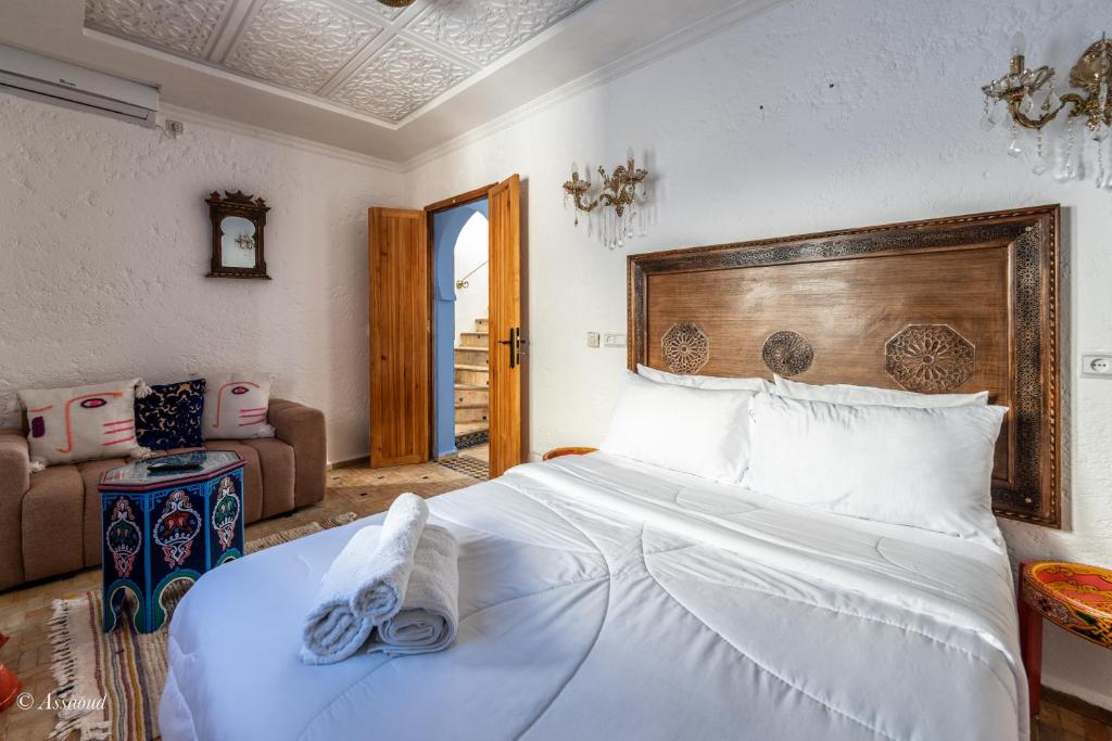 - une chambre avec un grand lit blanc et une tête de lit en bois dans l'établissement Dar Bleu main, à Chefchaouen