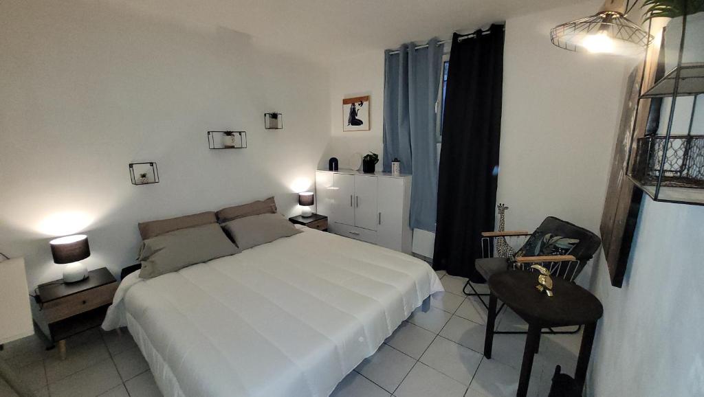 une chambre avec un lit blanc et une chaise dans l'établissement BEACH APPART, à Nice