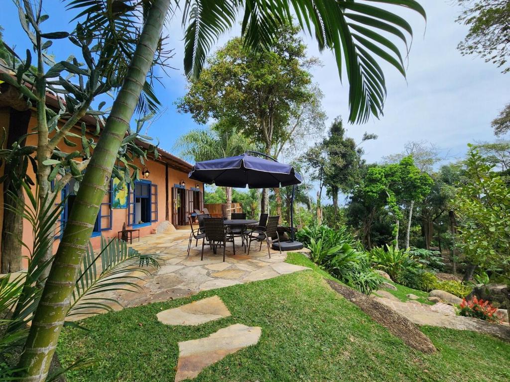 een patio met een tafel en een parasol bij Bangalô Sol · Bangalô Sol: refúgio c/ vista incrível em Ilhabela in Ilhabela