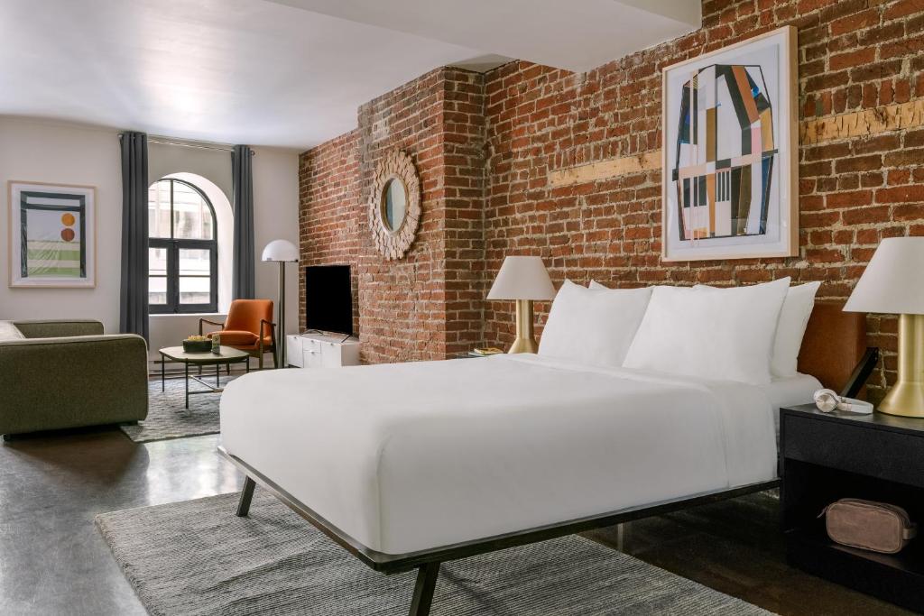 a bedroom with a white bed and a brick wall at Sonder Penny Lane in Montreal