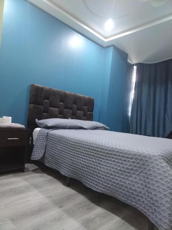 een slaapkamer met een bed met een blauwe muur bij Hostal Blue Royal in Quito