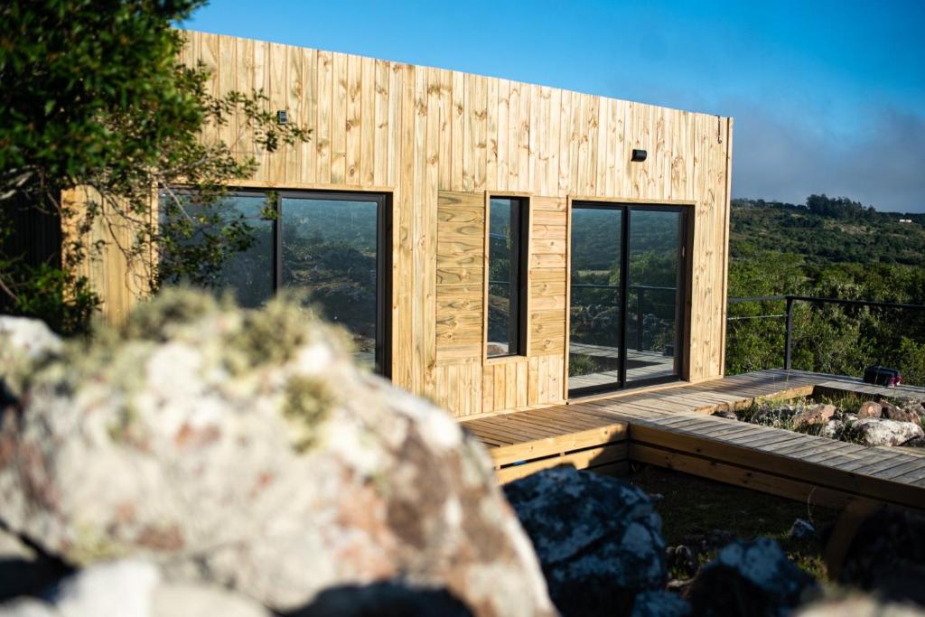 a wooden house with a deck and windows at El Secreto en las Sierras in Villa Serrana