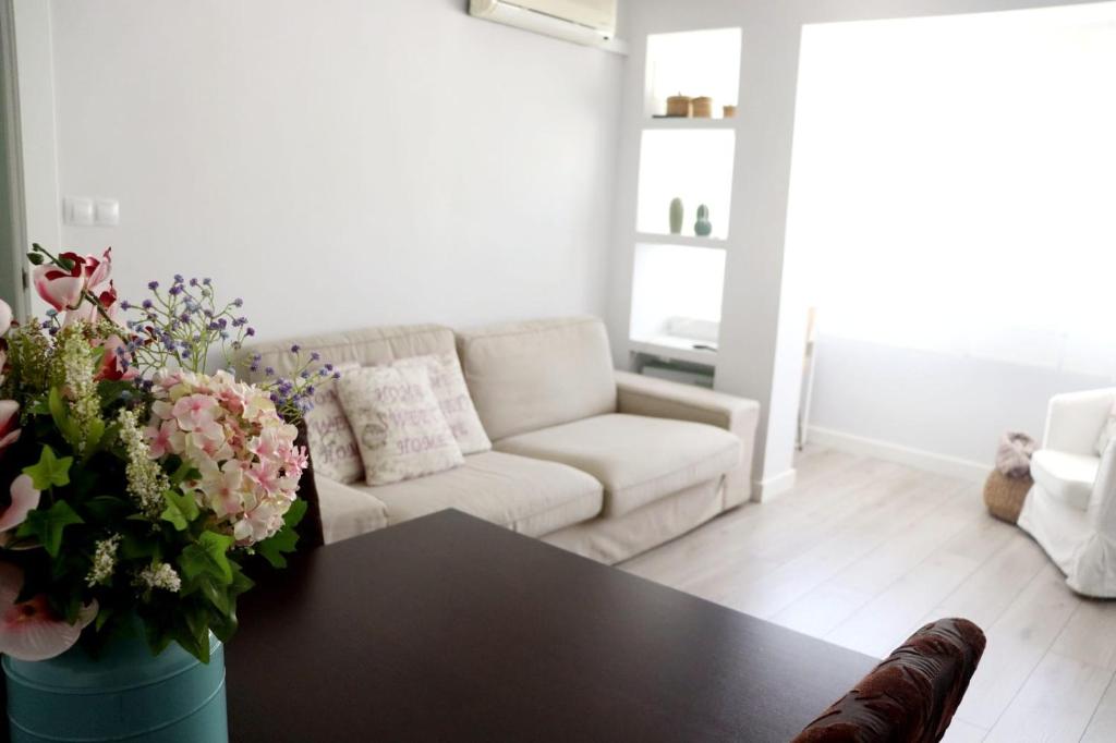 sala de estar con sofá y mesa con flores en La morada del viajero, en Granada