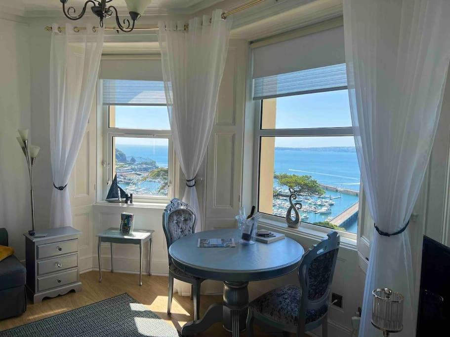 a room with a table and chairs in front of a window at Waterside & Marina View Apartment in Torquay in Torquay