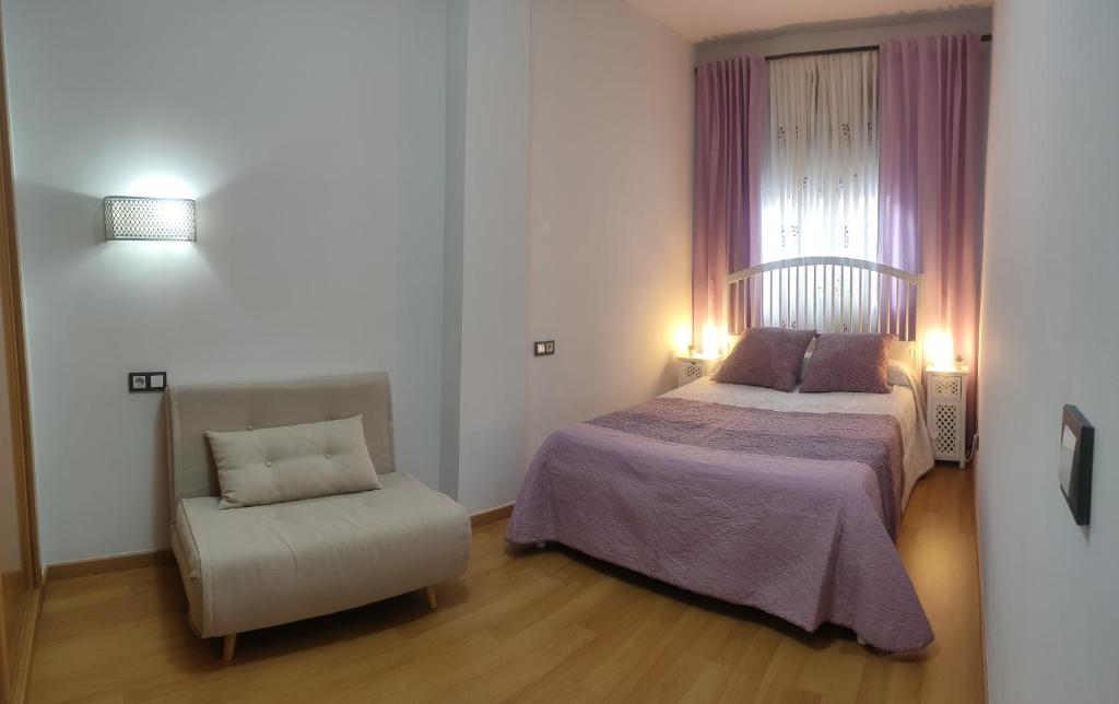 um quarto com uma cama e uma cadeira em Ático - Piscina Málaga centro em Málaga