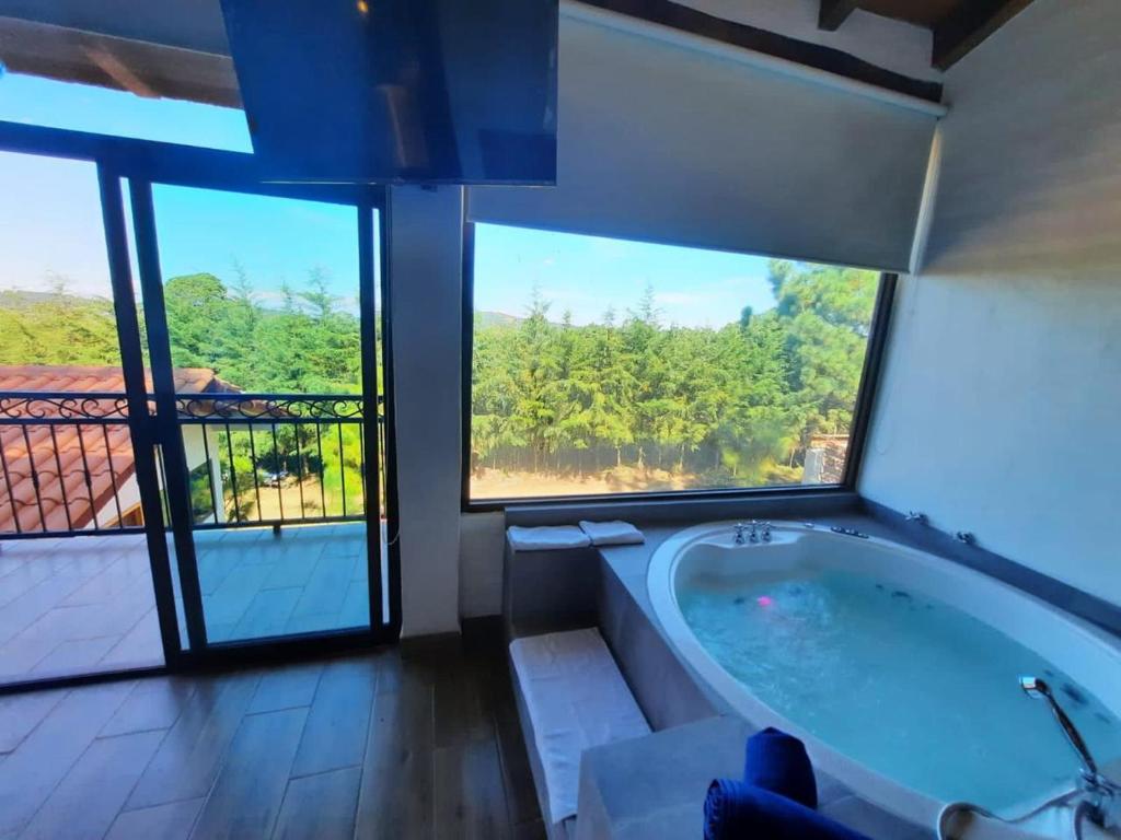 uma casa de banho com uma banheira grande e janelas grandes em El Roble de los Abuelos Hotel de Montaña Colibri em Mazamitla