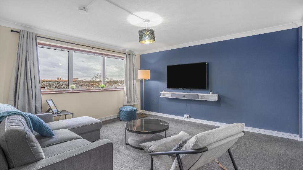 uma sala de estar com um sofá e uma televisão numa parede azul em Park Avenue - An Executive 2 Bed Suite with a Private Bathroom in Birmingham City Centre, 5 mins to City Hospital em Birmingham