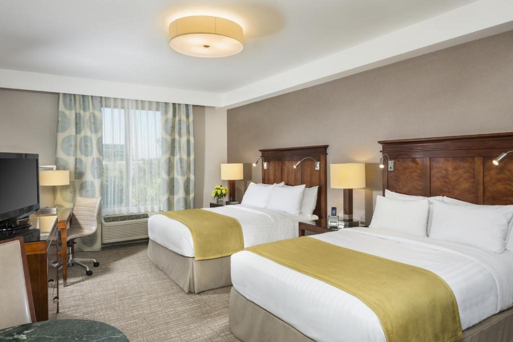 um quarto de hotel com duas camas e uma televisão de ecrã plano em Ayres Hotel Anaheim em Anaheim