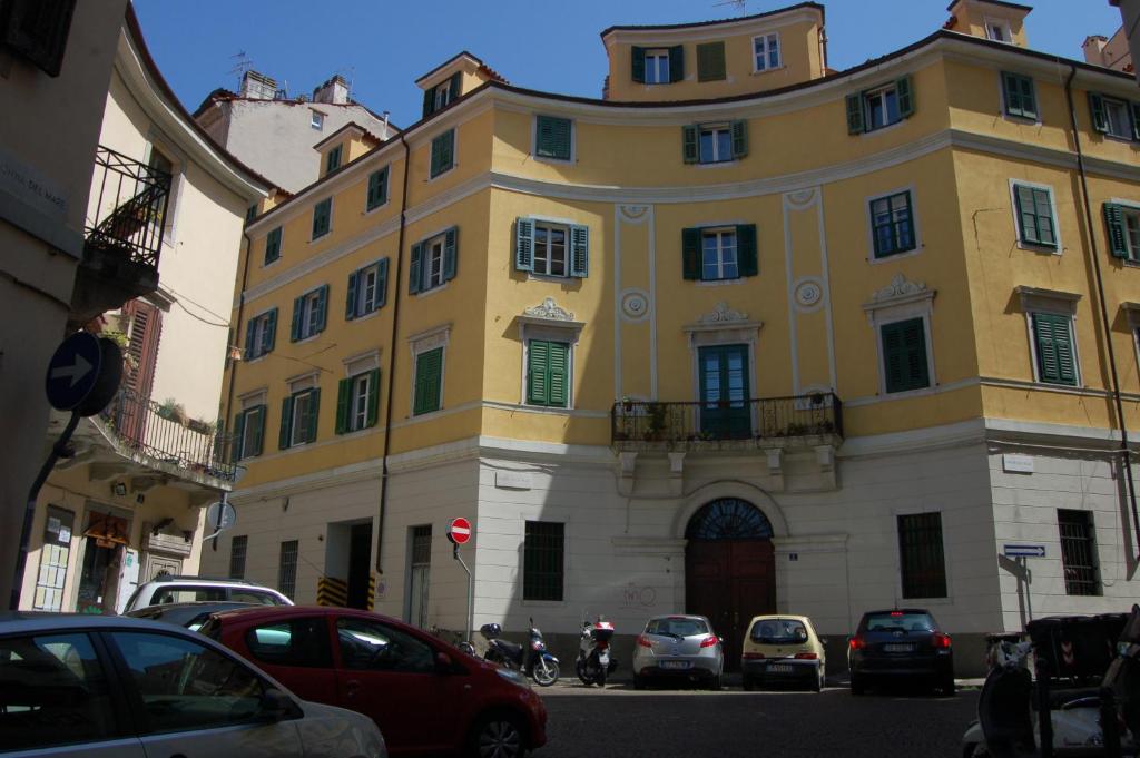 un grand bâtiment jaune avec des voitures garées devant lui dans l'établissement Appartamenti della Valle, à Trieste