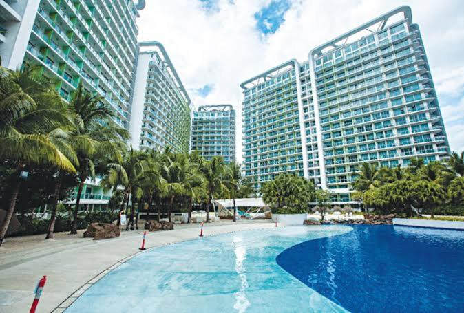 a large swimming pool with palm trees and tall buildings at 1-BR Vintage Condotel - Azure Resort in Manila