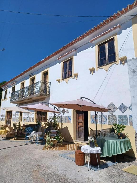 a building with a table and umbrellas in front of it at Casario do Vale Hospedagem e Eventos in Assento