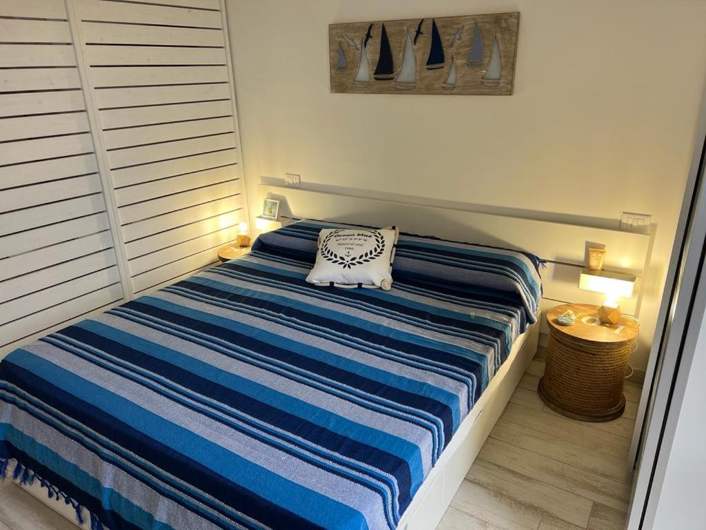 una camera con un letto con una coperta a righe blu e bianche di Isola di Marettimo casa vacanze a Marettimo