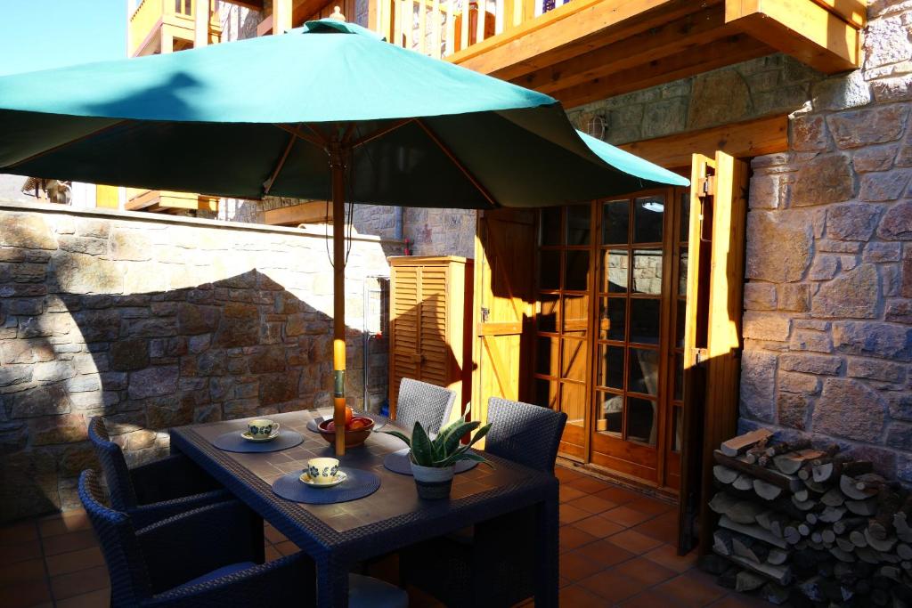 una mesa con una sombrilla azul en el patio en Can Vilà- Vall de Camprodon, en Vilallonga de Ter