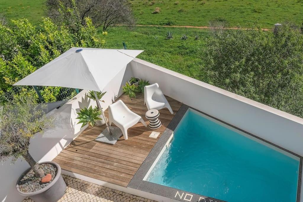 einen Pool mit 2 Stühlen und einem Sonnenschirm in der Unterkunft Unique Townhouse ~ Private pool ~ Rooftop terrace in Luz
